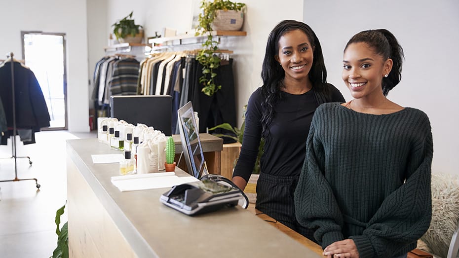 Two women smiling behind the counter in clothing store